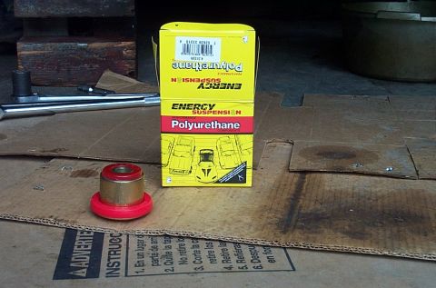 1995 Ford Bronco - A new red Energy Suspension polyurethane bushing with metal sleeve sitting on cardboard next to its yellow and red Energy Suspension Polyur…
