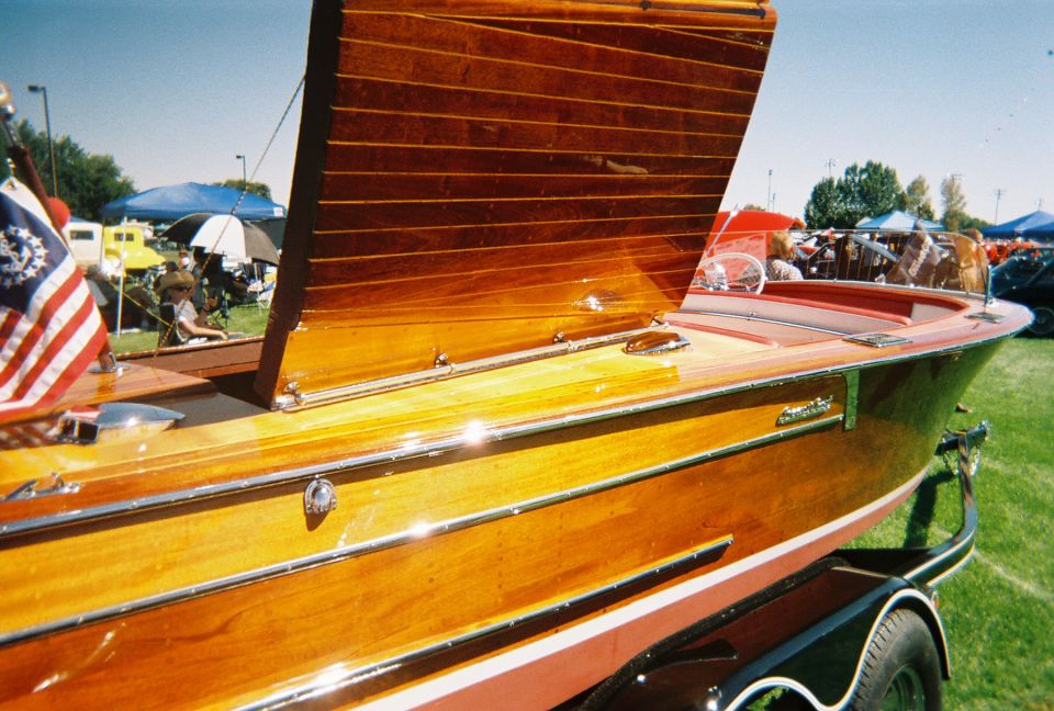 Wooden boat on a trailer, American flag on the left, people and tents in the background