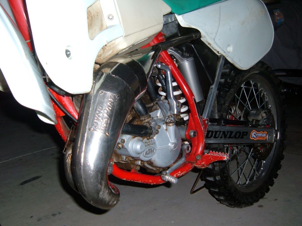 Close-up of a motorcycle's DynoJet exhaust pipe and engine components, with Dunlop tire visible