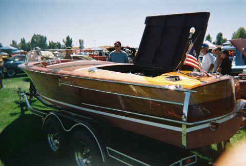 1972 Ford Ranchero - A classic wooden boat is displayed on a trailer at an outdoor event, with other vehicles visible in the background.