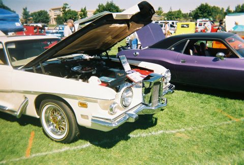 1972 Ford Ranchero - A cream-colored car with its hood open is displayed on grass next to a purple car at an outdoor event.