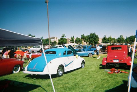 1972 Ford Ranchero - Several classic cars are displayed on a grassy field under a clear blue sky at an outdoor car show.