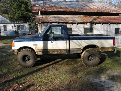 1989 Ford F-150 - This 1989 Ford F-150 pickup truck is shown in profile, a two-tone paint scheme and lifted suspension with oversized tires.