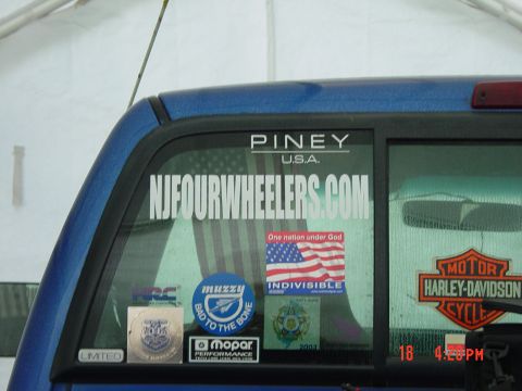 1995 Dodge 1500 - Rear window of a blue pickup truck displays various stickers, including a website and a motorcycle brand logo.