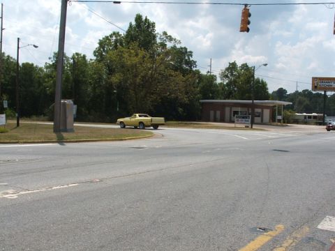 1972 Ford Ranchero - A yellow 1972 Ford Ranchero is seen driving on a road near a building.