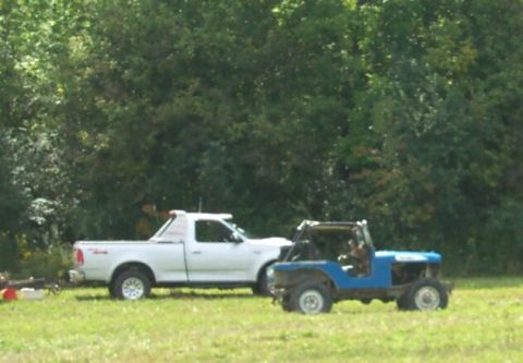 1979 Ford F-150 - A white pickup truck and a blue jeep are parked next to each other on a grassy field with trees in the background.