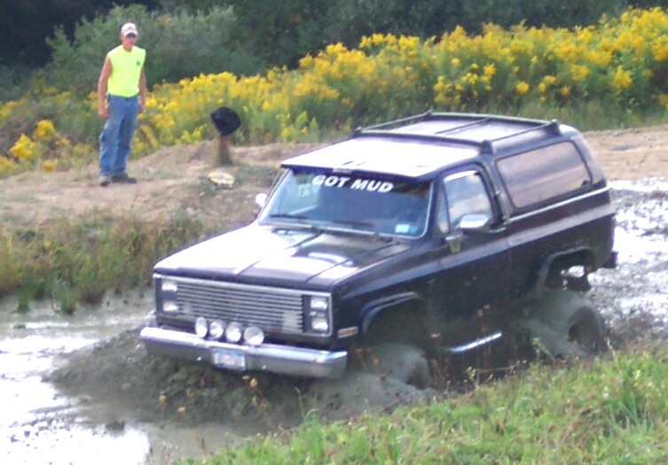 Black SUV stuck in mud with 'GOT MUD' sticker on windshield