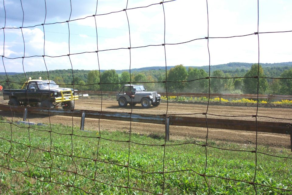 Black pickup truck with yellow bumper and a gray jeep on a dirt track