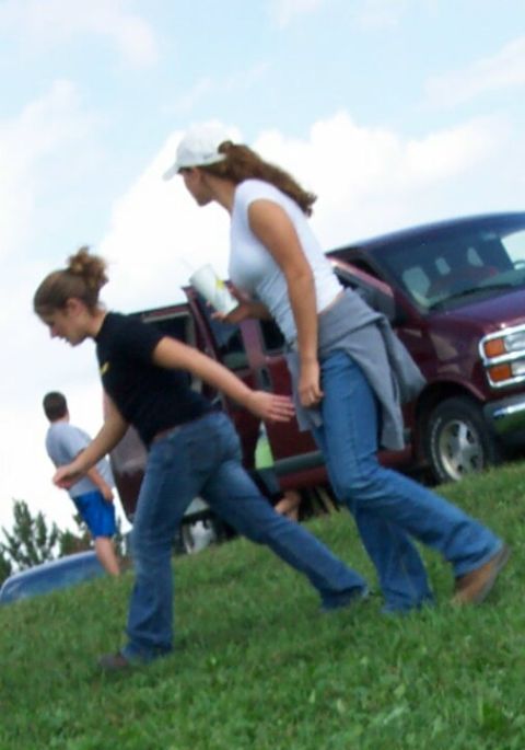 1979 Ford F-150 - Two women walk past a maroon van parked on a grassy incline under a cloudy sky.