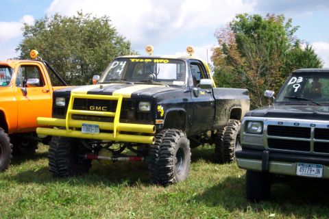 1979 Ford F-150 - A modified GMC pickup truck is parked on grass next to other vehicles under a cloudy sky.