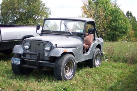 1979 Ford F-150 - A gray Jeep CJ-5 is parked next to a pickup truck in a grassy field.