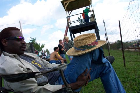 1979 Ford F-150 - Spectators gather at an outdoor event, with a man relaxing in the foreground and a viewing tower in the background.
