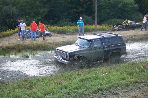 1979 Ford F-150 - Two off-road vehicles navigate a muddy terrain, with spectators watching.