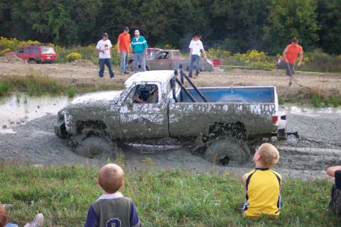 1979 Ford F-150 - Spectators watch as a heavily mud-covered pickup truck becomes stuck in a mud pit during an event.