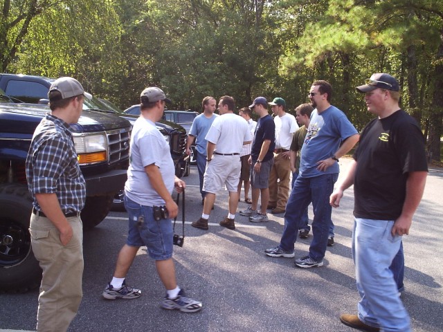 Group of people talking in a parking lot beside a dark lifted truck