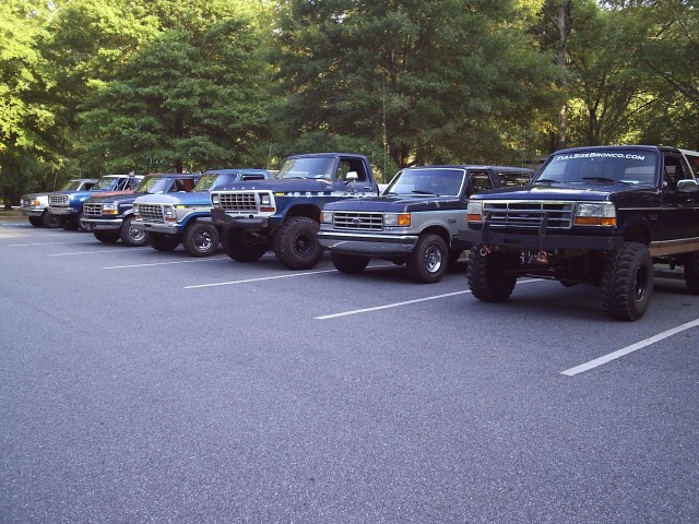 Row of full-size Ford Broncos parked at a club meet, lifted black Bronco with winch nearest