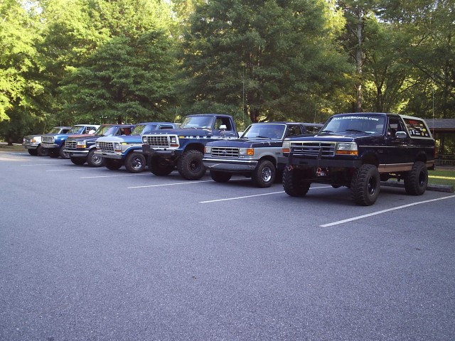 Row of lifted dark-blue Ford Broncos parked at a club meet