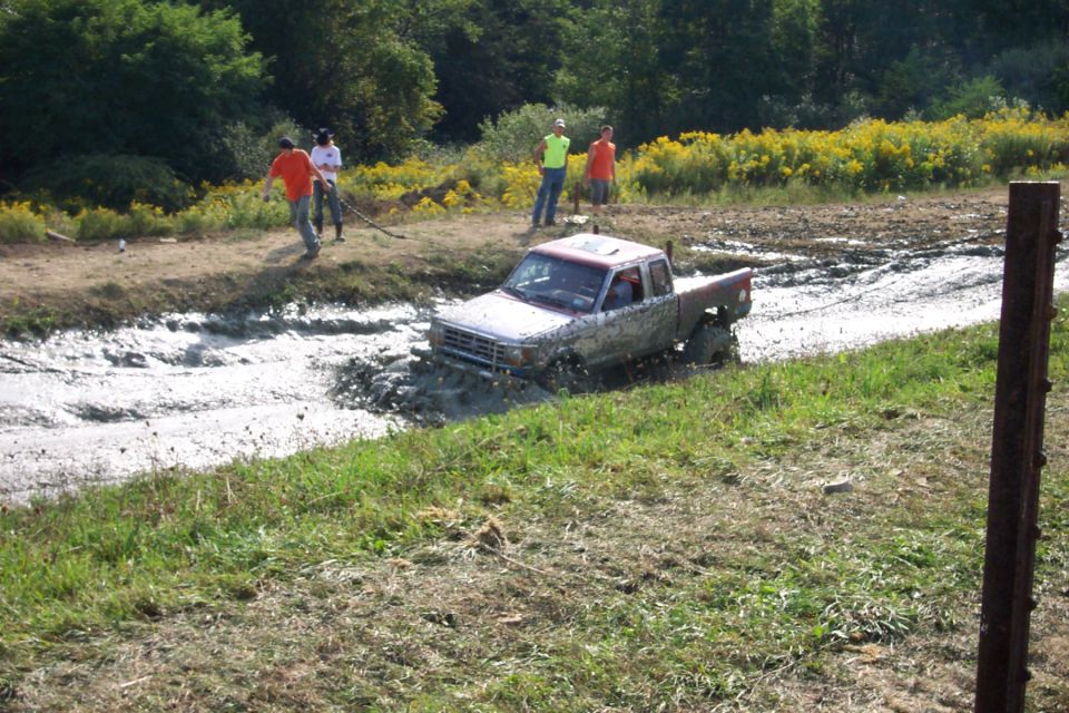 Silver pickup truck stuck in mud pit, 3/4 front view