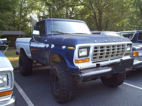 1989 Ford Bronco - This lifted Ford pickup truck features a prominent exhaust stack and a two-tone paint scheme.