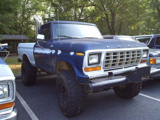 Late-1970s lifted blue-and-white Ford pickup with exhaust stack, front three-quarter