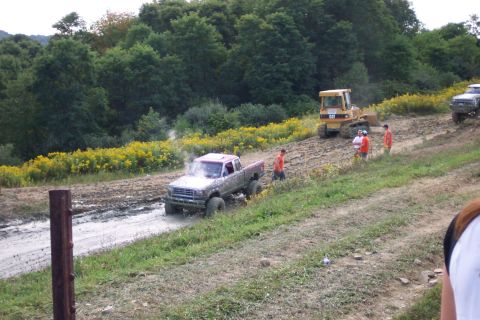 1979 Ford F-150 - A pickup truck navigates a muddy terrain, with a bulldozer and several people observing the scene.