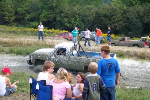 1979 Ford F-150 - Several vehicles are stuck in a mud pit as onlookers observe the off-road event.