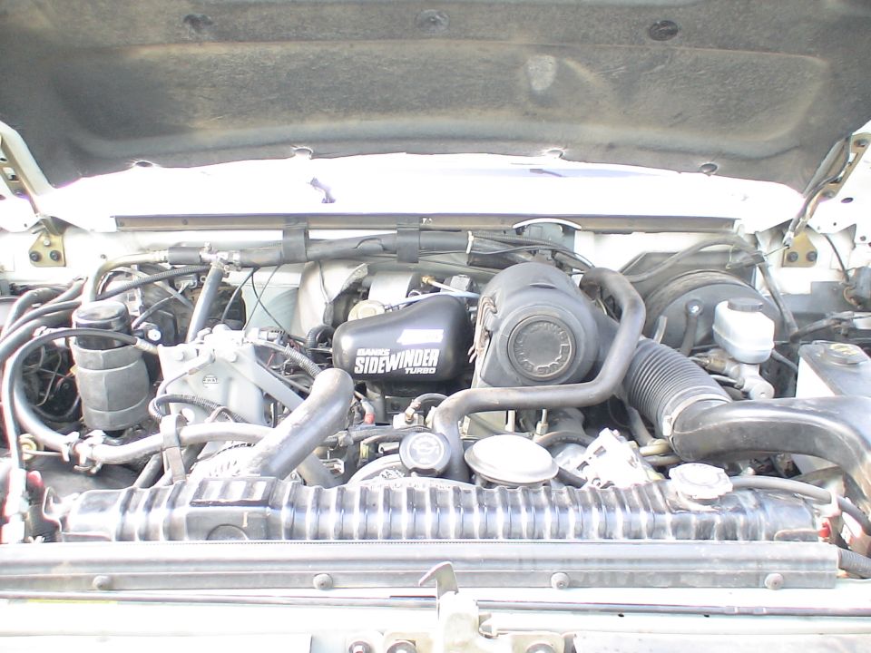 Open engine bay with Sidewinder supercharger or component, air intake and radiator visible