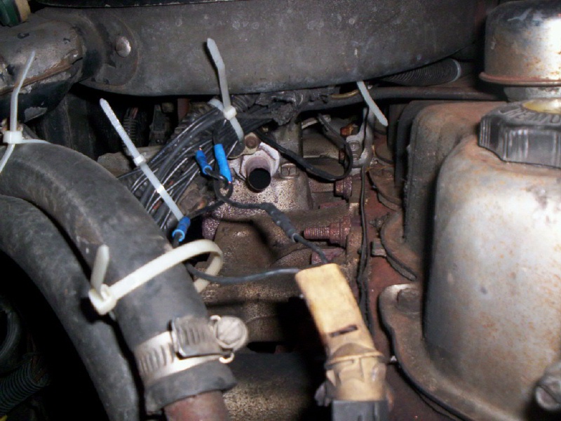 Greasy engine area with cable-tied wiring and a thermostat housing
