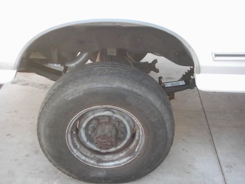 1978 Ford Bronco - Close-up of the rear wheel and suspension system of a white vehicle.