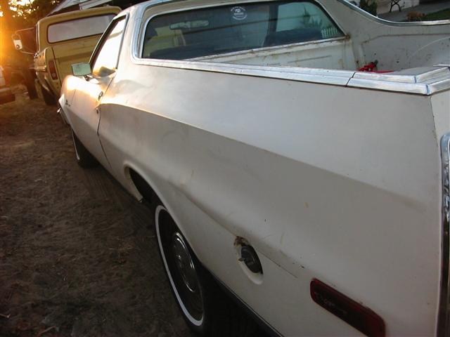 White 1972 Ford Ranchero, side view, showing dent on rear quarter panel and a yellow truck in the background