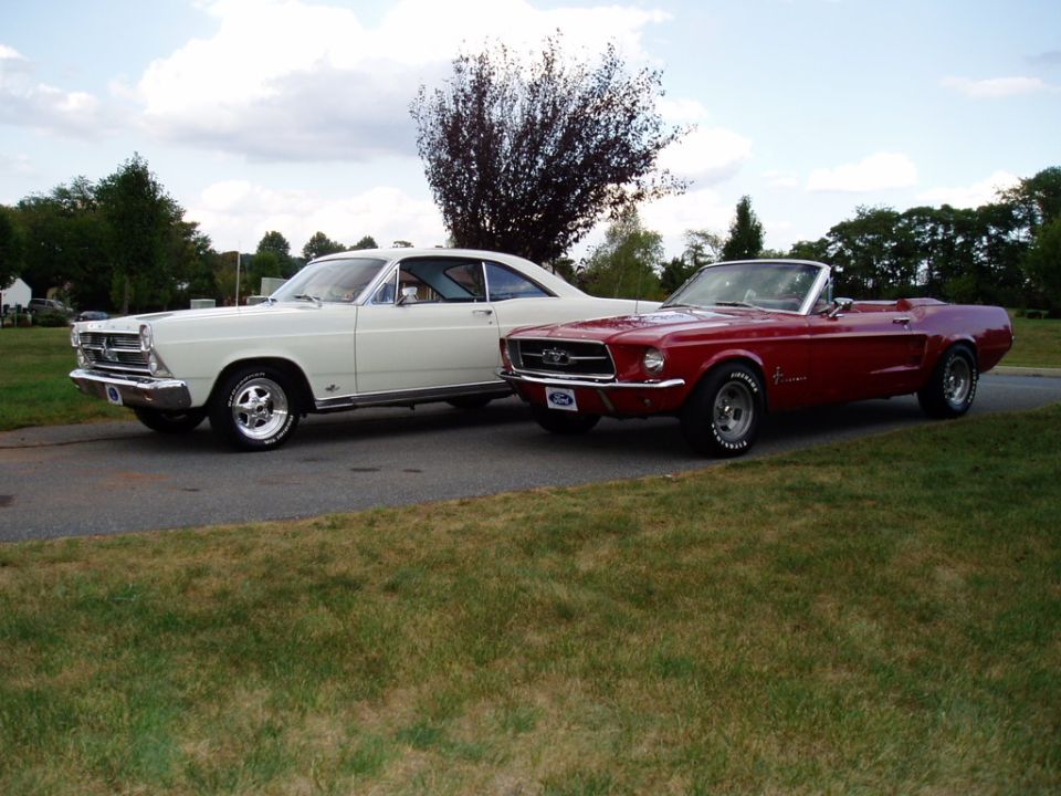 Red 1967 Ford Mustang convertible and a white 1966 Ford Fairlane parked on a road