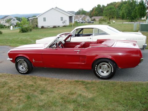 1967 Ford Mustang - A red 1967 Ford Mustang convertible is parked beside a white coupe in a residential area.