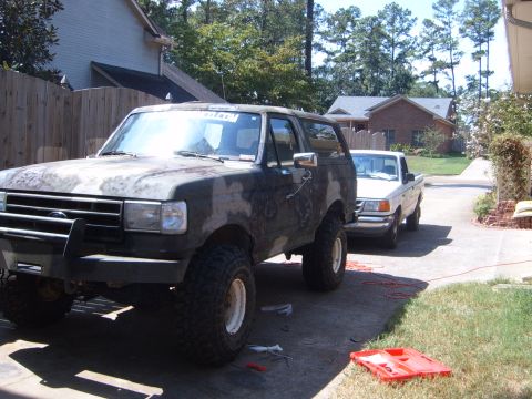 1988 Ford Bronco - Two trucks, a Ford Bronco and a Ford Ranger, are parked in a driveway on a sunny day.