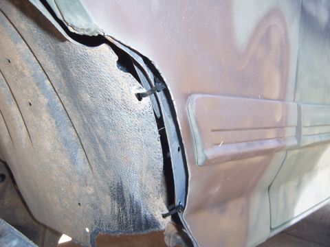 1988 Ford Bronco - The inner fender liner is torn and secured with clips, showing rust and wear.