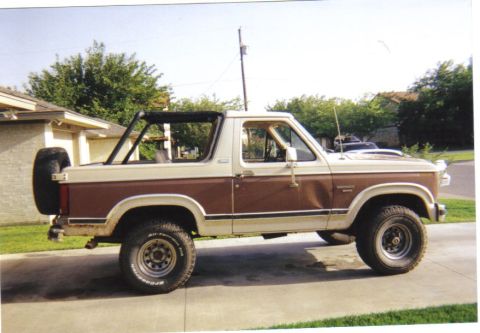 1982 Ford Bronco - This two-tone brown and white Ford Bronco is shown from the side, a spare tire mounted on the rear.
