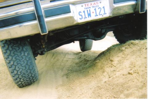1982 Ford Bronco - The rear axle and tires of a vehicle navigate a sandy incline, showing off-road capability.