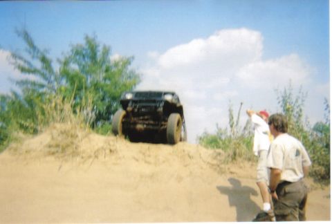 1982 Ford Bronco - Off-road vehicle navigates a sandy hill with onlookers present.