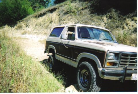 1982 Ford Bronco - This 1980s Ford Bronco is navigating a dirt road in a dry, grassy area.