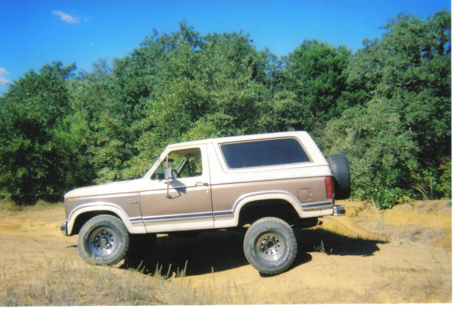 Two-tone brown and white 1982 Ford Bronco parked on dirt road