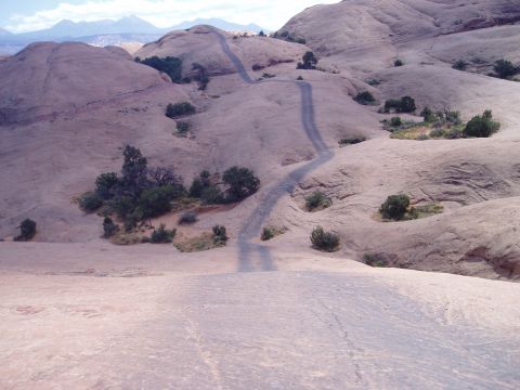 2000 Ford E350 - A winding dirt road traverses a desolate, rocky landscape under a hazy sky.