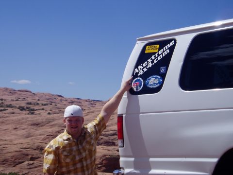 2000 Ford E350 - Close-up of the rear corner of a white van in slickrock desert country, showing a large AKextreme 4x4.com decal, a Kodiak Off-Road sticker…