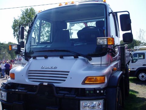 2000 Ford E350 - A silver Unimog truck is seen from the front, with "UNIMOG" visible on its grille.