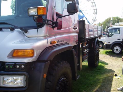 2000 Ford E350 - A silver Unimog truck is parked on grass with a Ferris wheel in the background.