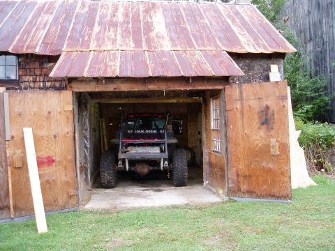 2000 Ford E350 - An off-road vehicle is parked inside a rustic wooden garage with the doors open.