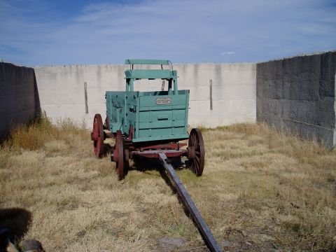 2000 Ford E350 - This vintage green wagon with red wheels is seen in a dry, grassy area with a concrete wall in the background.