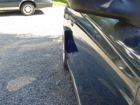 1995 Ford Mustang - Side view of a dark blue car parked on a gravel surface, with another vehicle visible in the background.