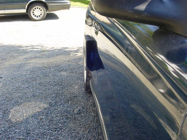 Dark blue car side view, another car in background