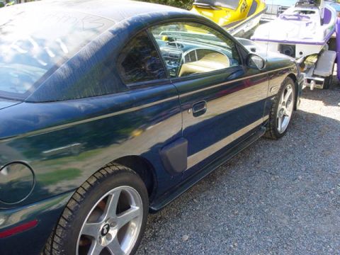 1995 Ford Mustang - A 1995 Ford Mustang coupe is parked next to a trailer carrying jet skis.
