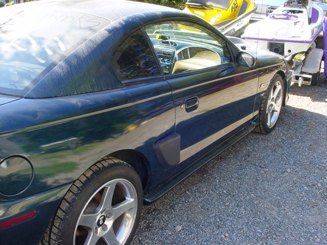 Dark green 1995 Ford Mustang coupe parked next to a trailer with two jet skis