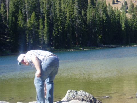 2000 Ford E350 - Man by a lake with pine trees and mountains in the background. Supermotors logo visible.